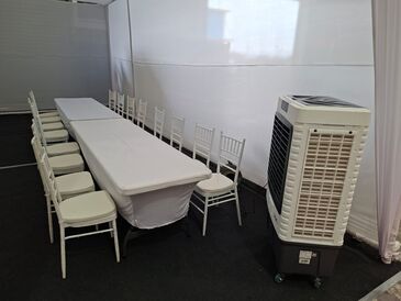 Enfriador de aire evaporativo junto a una mesa de banquetería en una carpa